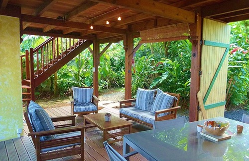 Pointe-Noire Cabaña | Bungalow rojo de madera en un parque con ambiente tropical.