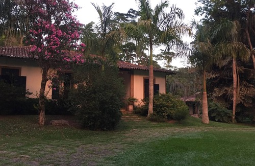 Correas Casa | Casa colonial con otras dos casas más pequeñas en el borde de un río y por el bosque.