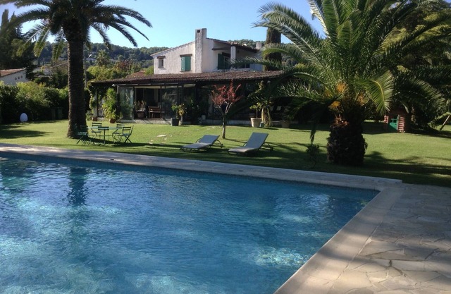 Hermosa y gran casa rodeada de un gran jardín con una piscina muy grande.