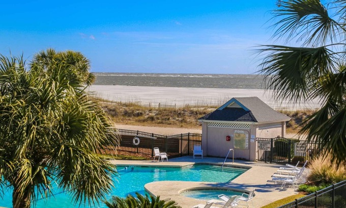Isle of Palms Condominio | Vea, sienta y escuche el océano desde este condominio lleno de luz con piscina comunitaria y porche privado con mosquitero.