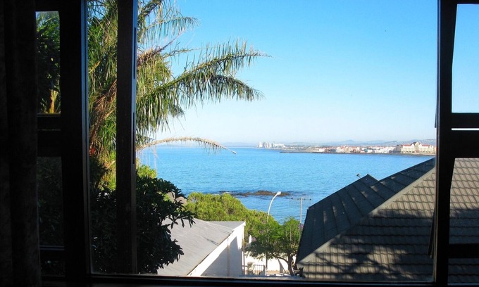 Gordons Bay Central Casa | Casa familiar soleada y abierta, sobre la playa al atardecer, con vistas al mar y a la montaña.